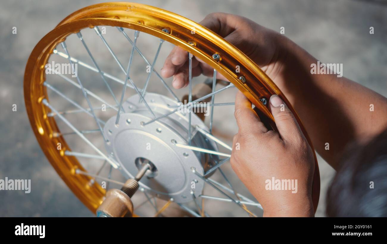 Technician man working motorcycle wheel has spokes weave up on mechanic