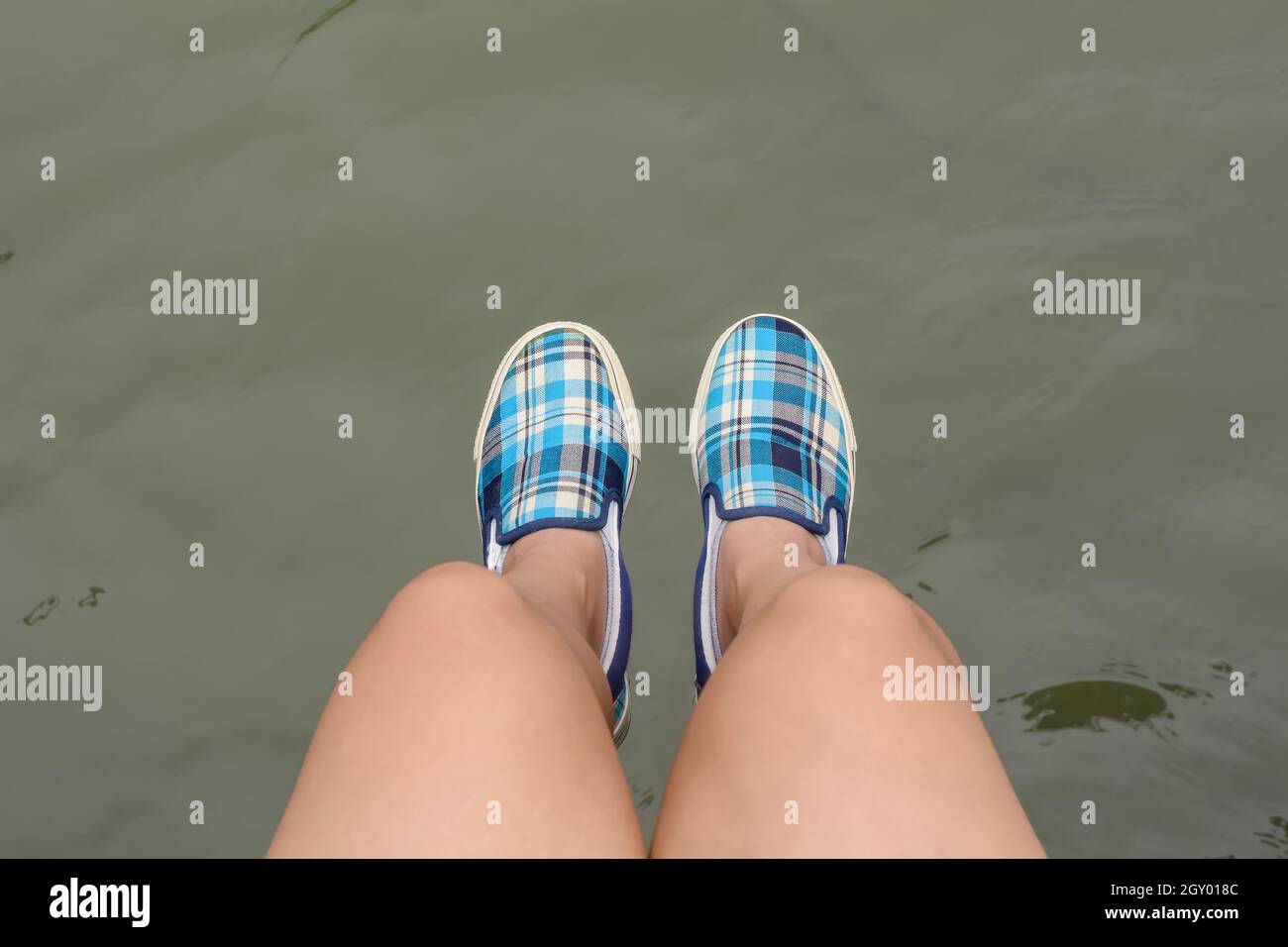 Girl wearing canvas sneakers sitting on the wooden bridge Stock Photo ...