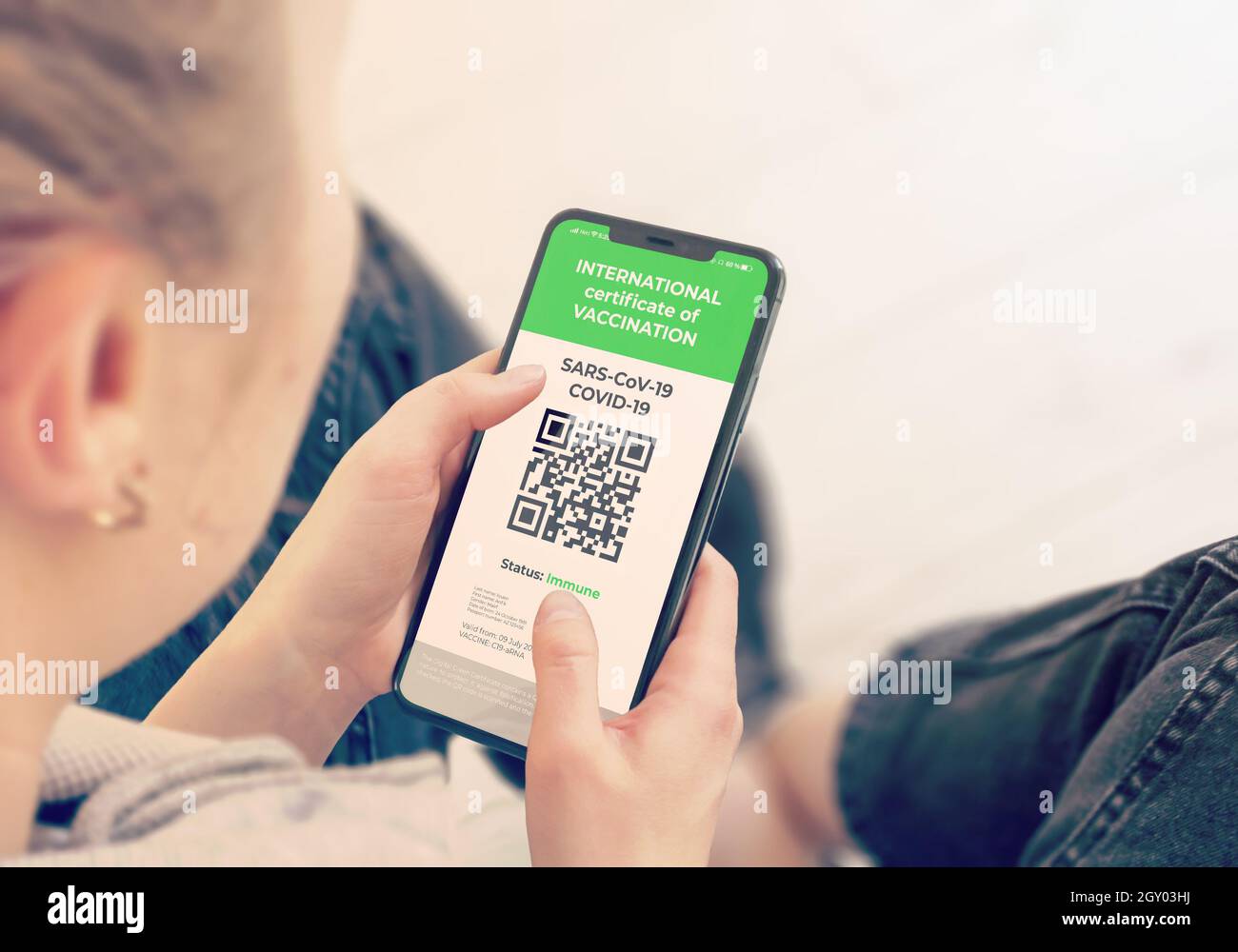 COVID-19: Digital green certificates on Cellphone Screen. Young Girl Takes Smartphone with Vaccinated digital health passport. Stock Photo