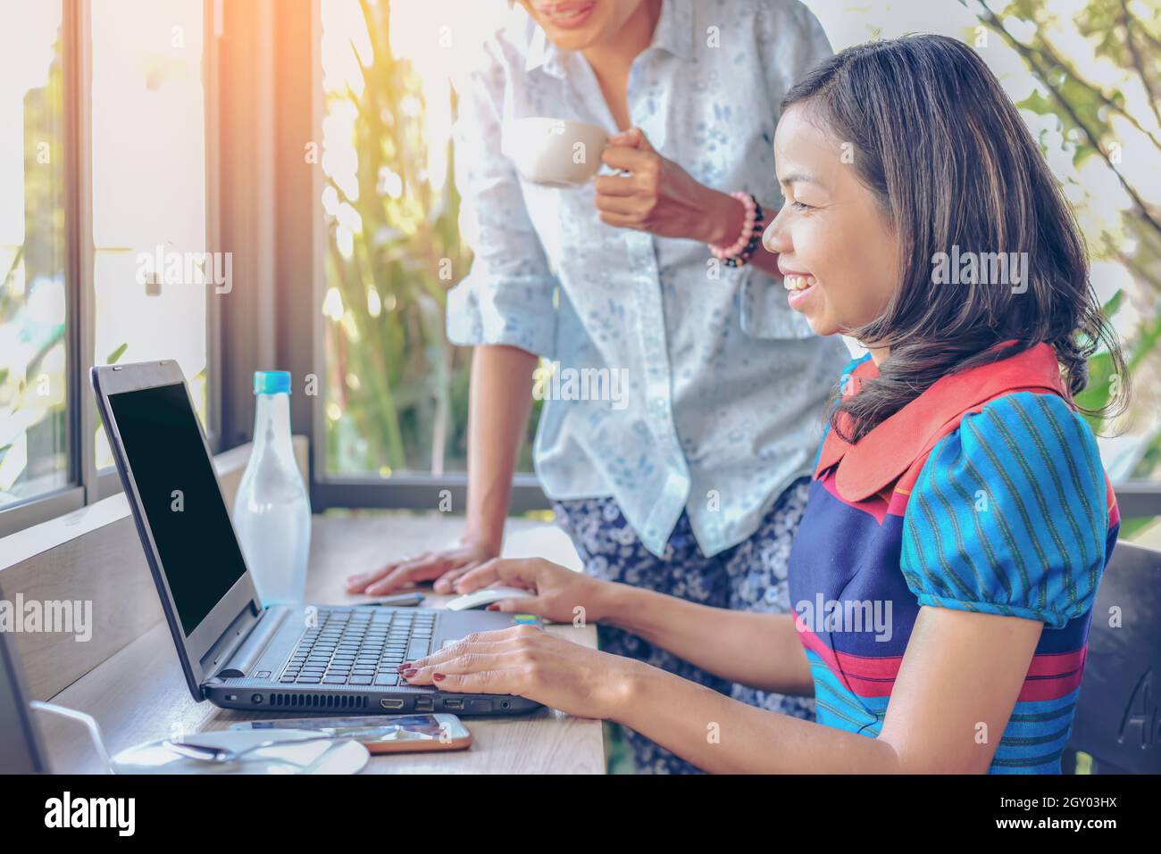 Image close up of couple asia woman using notebook with tablet while relaxing at cafe with matcha cake, Home worker working outside of company concept Stock Photo
