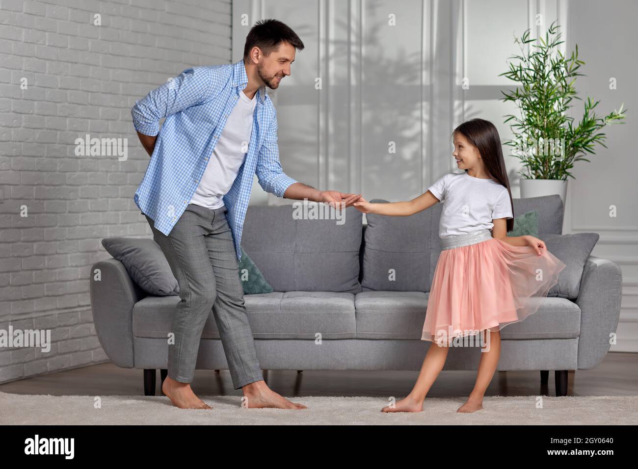 Handsome dad dancing with his little cute daughter at home. Father's Day Stock Photo