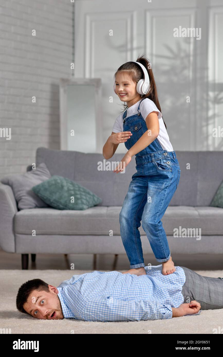 funny little child daughter doing massage to father and listening to music  at home Stock Photo - Alamy