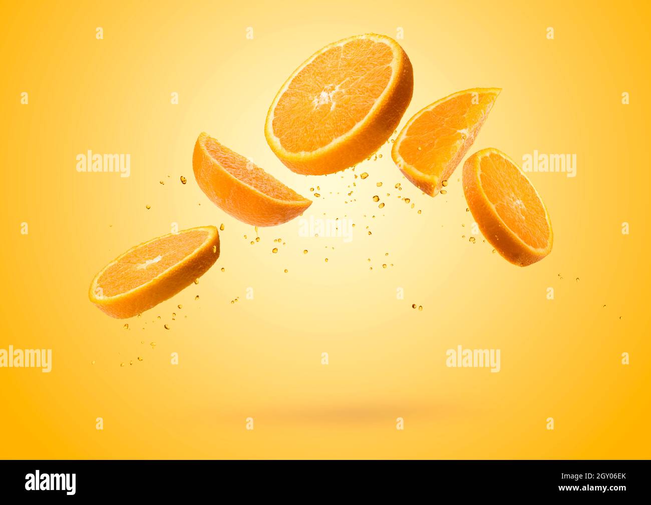 Orange fruit slices flying and dripping on colored background Stock Photo