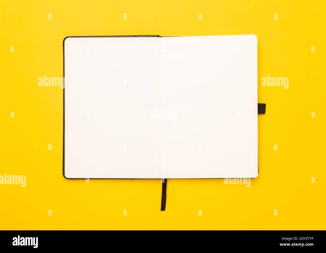 Black notebook opened isolated on yellow background. Stock Photo