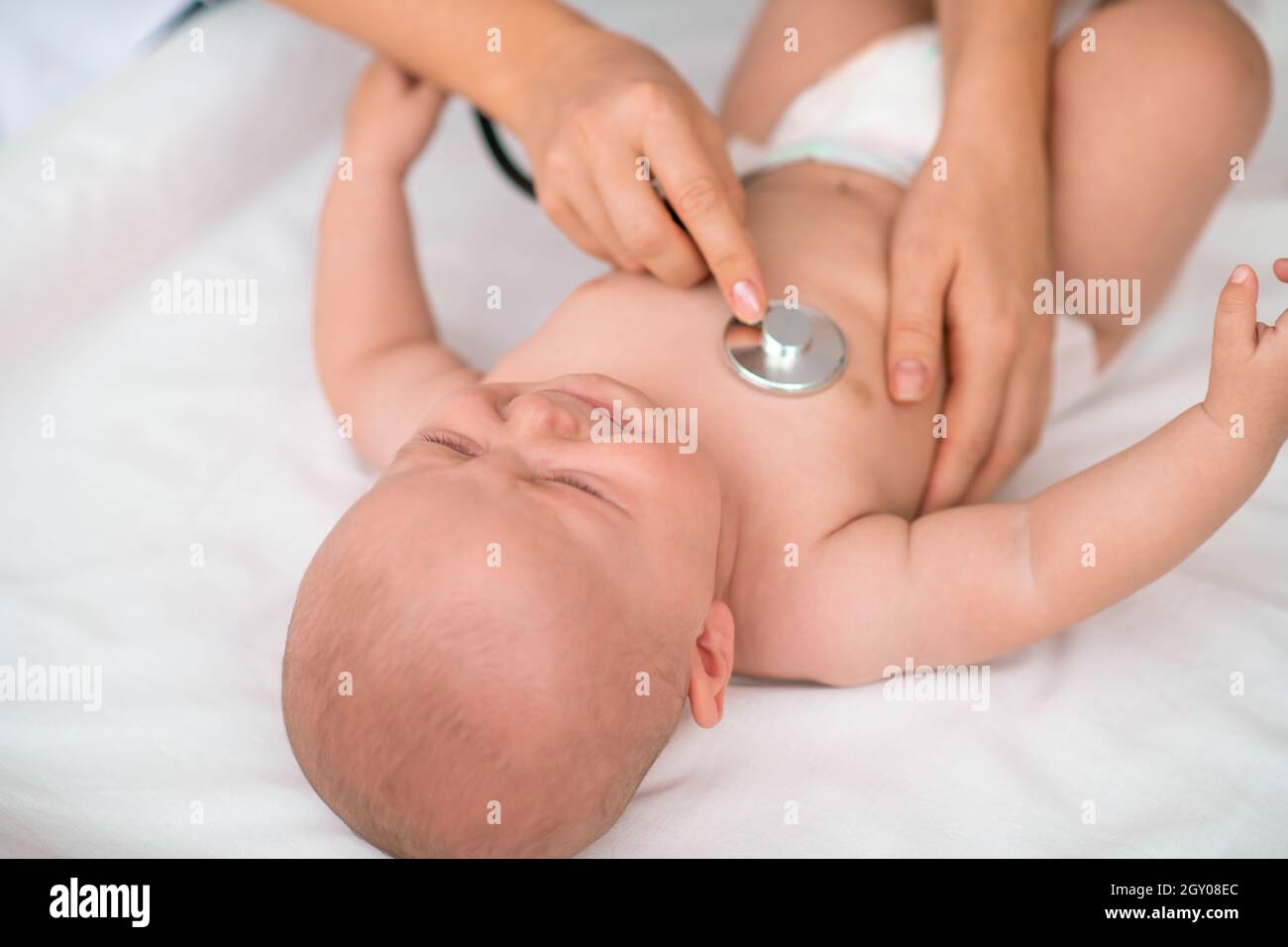 Crying infant being auscultated by an experienced pediatrician Stock Photo