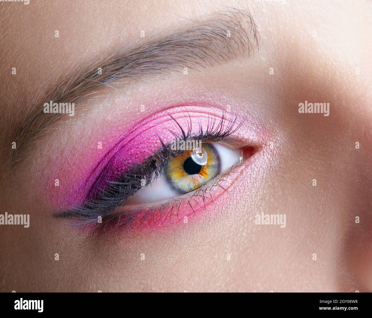 Closeup macro shot of human female eye. Woman with natural evening vogue face beauty makeup. Girl with perfect skin and pink eyes shadows. Stock Photo