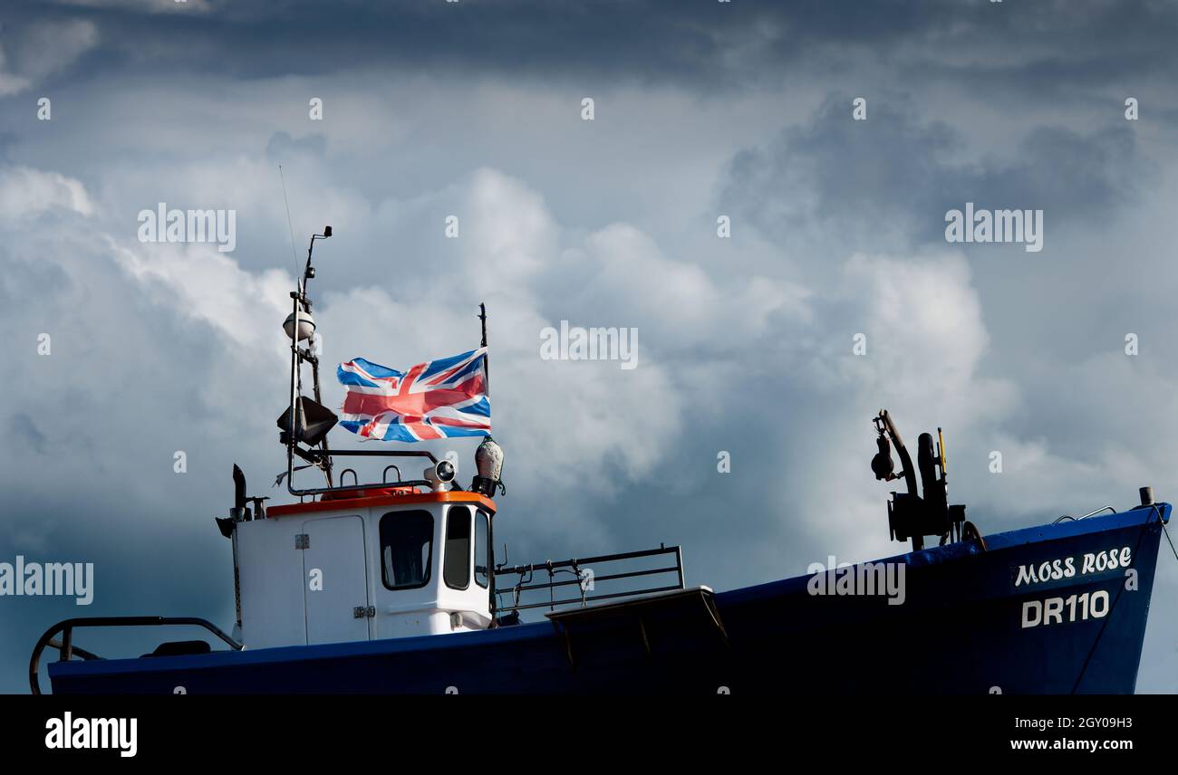 Dark clouds gather over UK fishing trawler with the British Union Jack flying Stock Photo