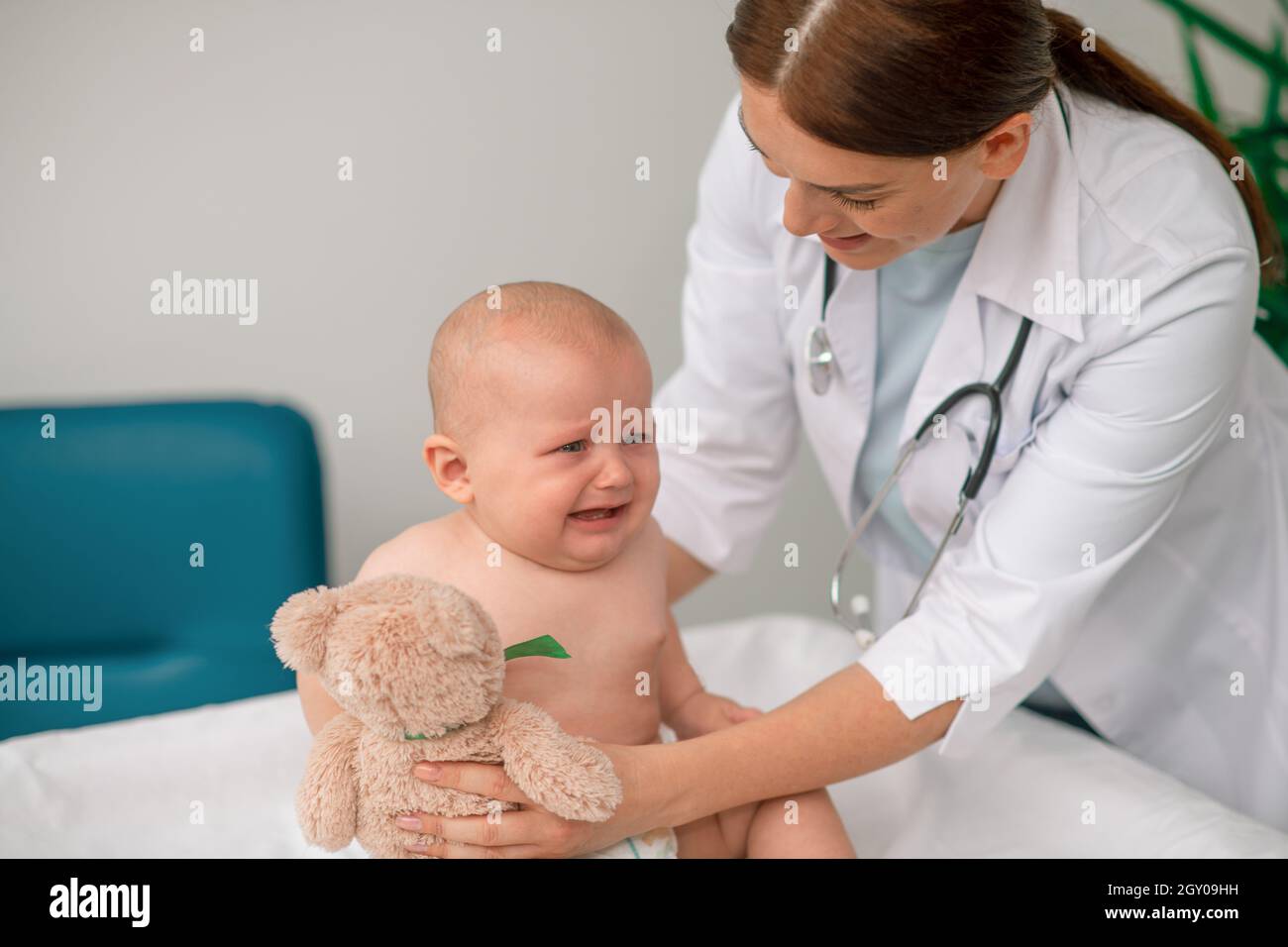 Caring doctor giving a toy to a crying baby Stock Photo