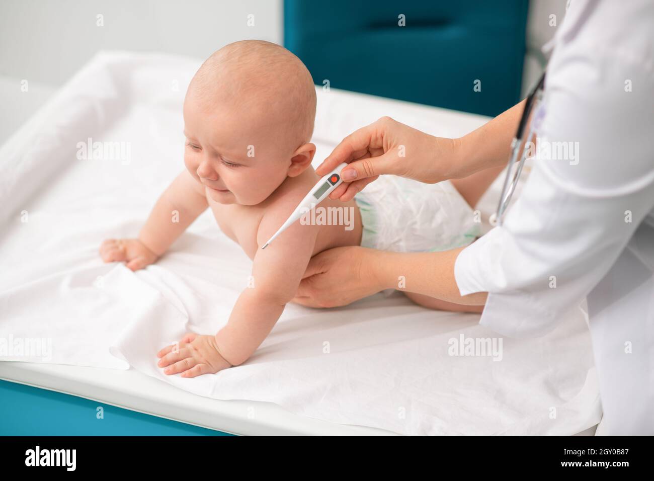 Experienced Caucasian female pediatrician taking baby temperature Stock