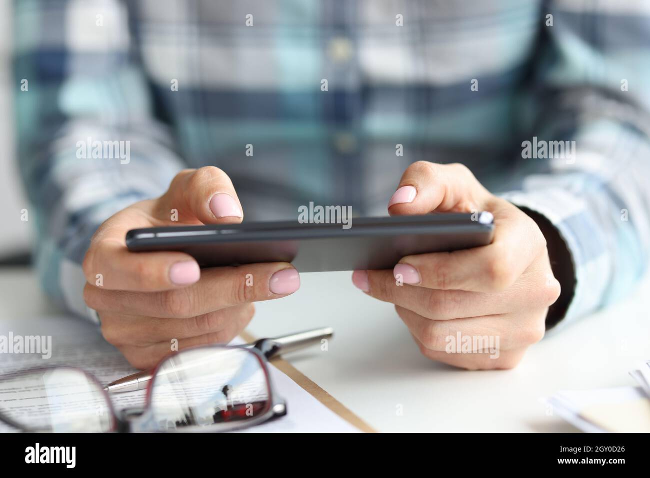 Black smartphone in female hands at workplace Stock Photo