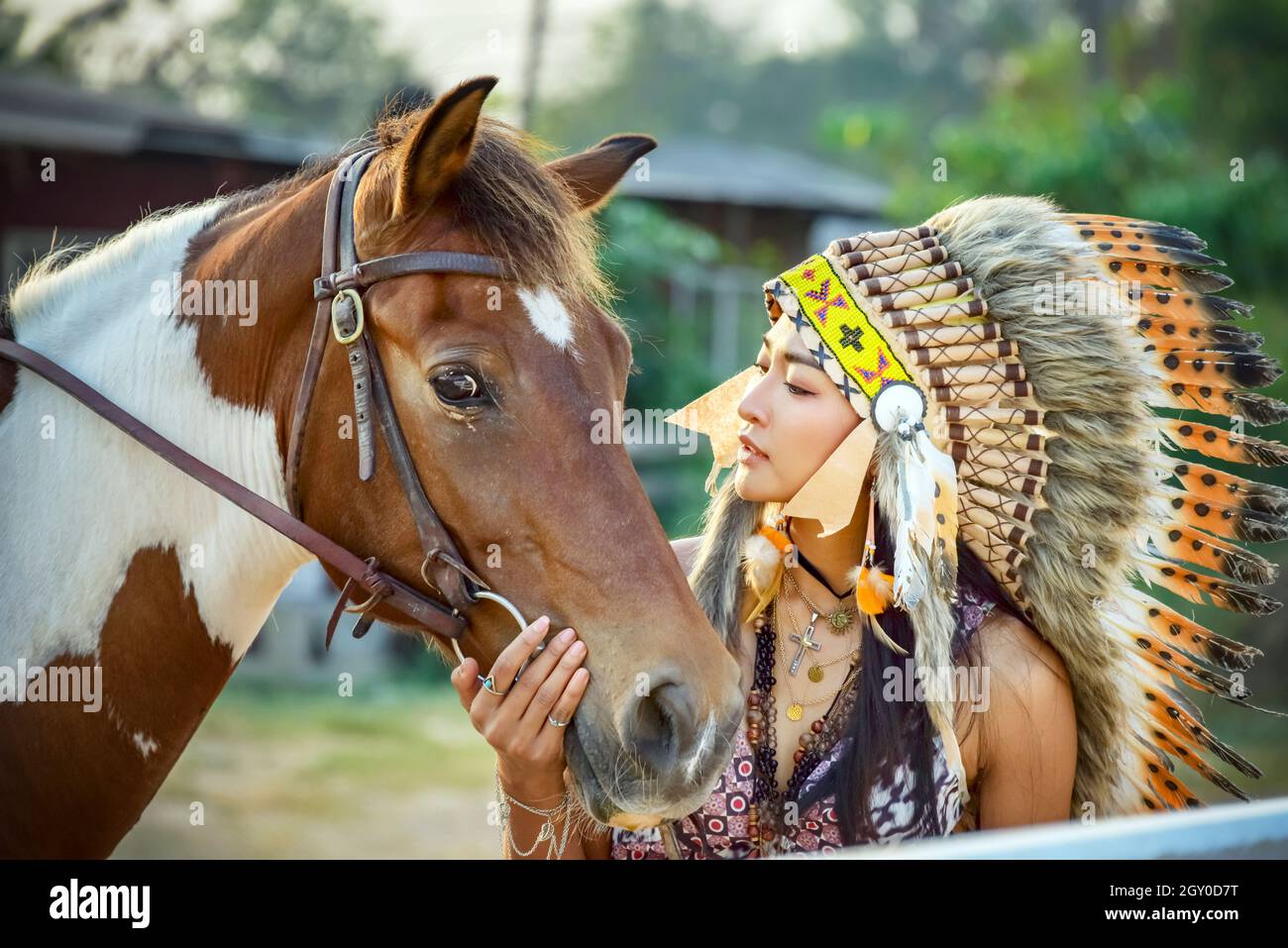 horse closeup with beautiful Bohemian girl  and beauty red brown horse. Injun Woman in war bonnet beauty portrait  Native American feather chief headd Stock Photo