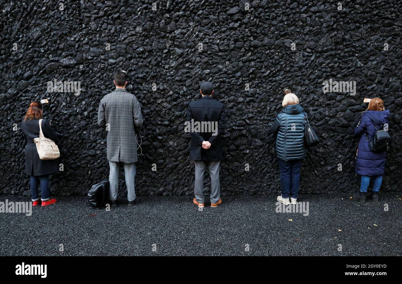 People take part in a by artist Marina Abramovic next to her artwork "Crystal Wall of Crying" at Yar, the site of one of the biggest massacres of the Holocaust