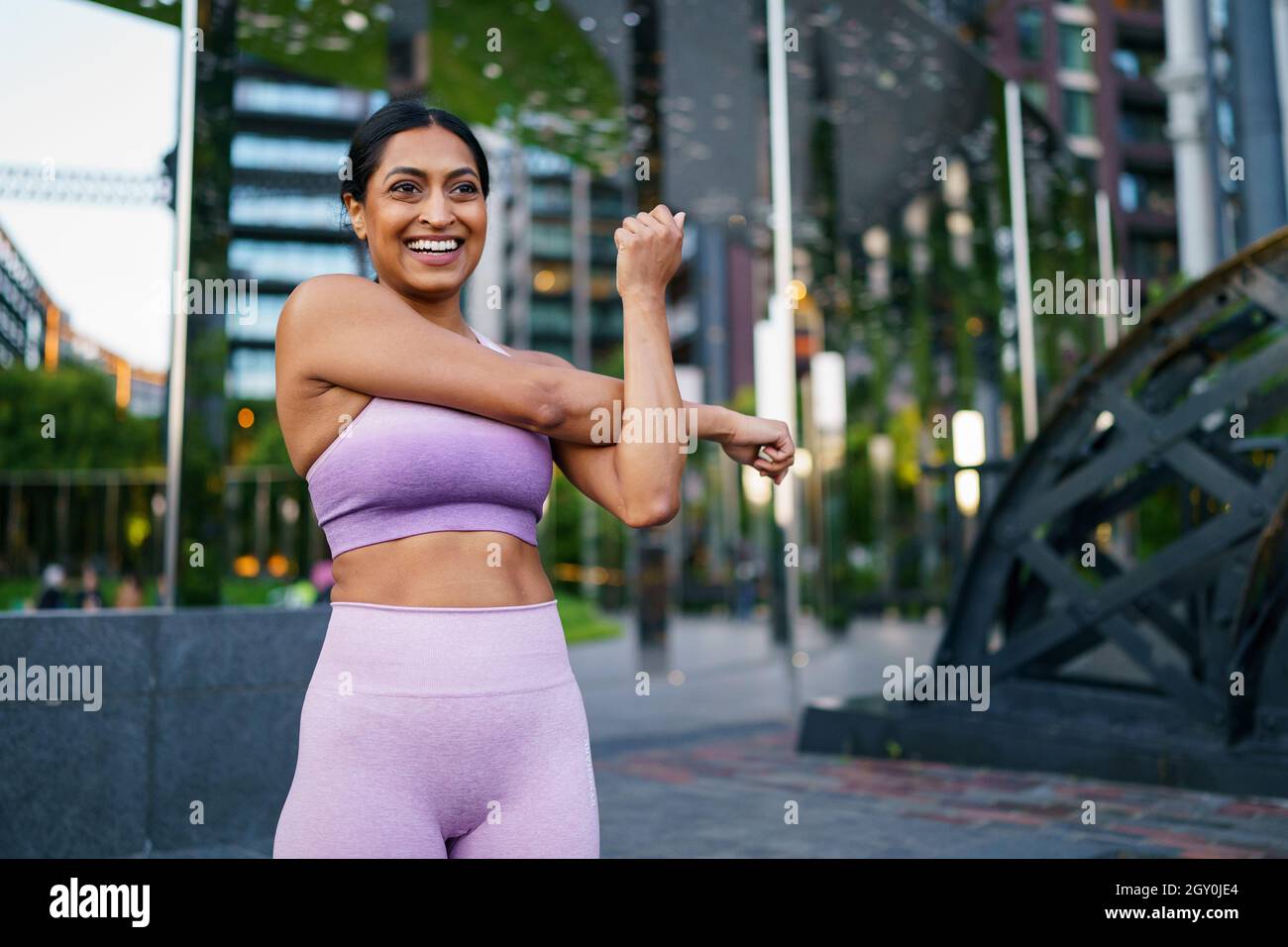 Woman in a pink outfit stretching before a workout in an urban setting Stock Photo