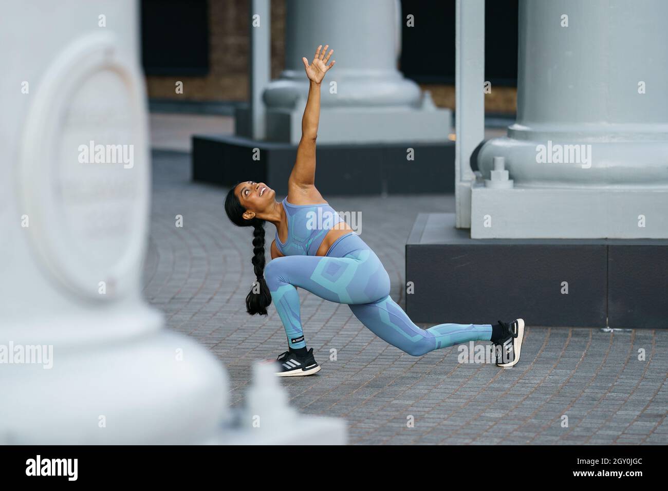 Woman in a grey outfit stretching before a workout in an urban setting Stock Photo