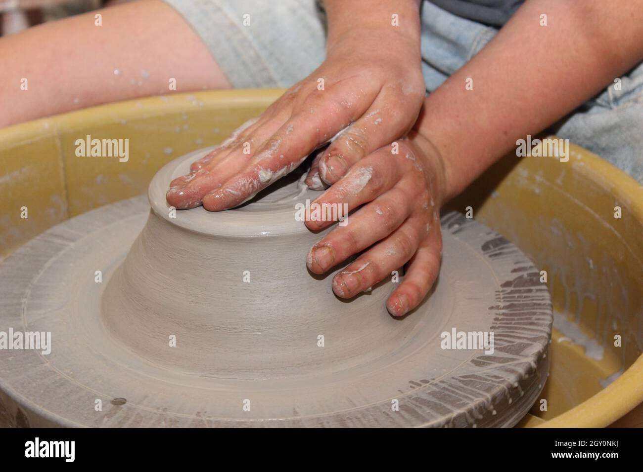 Working with clay in a pottery studio throwing a pot on the potter's