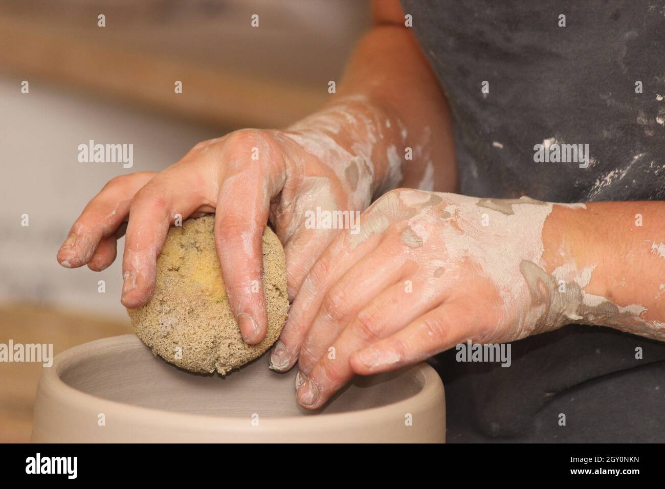 Working with clay in a pottery studio throwing a pot on the potter's