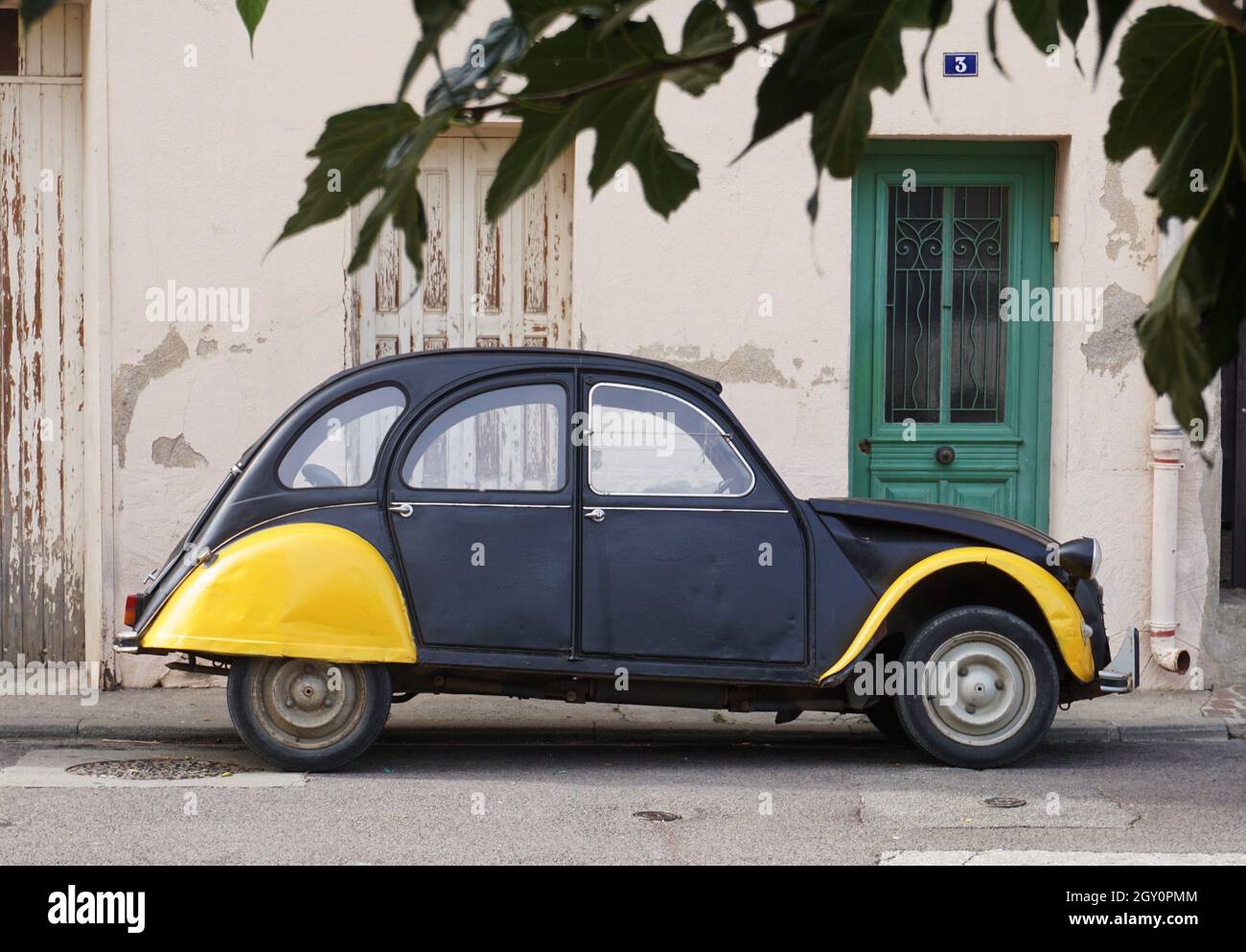 Vintage Citroen 2CV car, black and yellow in colour parked on street outside house on street in village in France Stock Photo