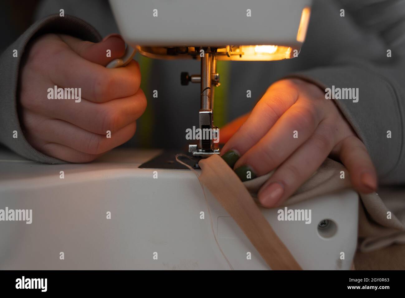 Sewing process, closeup of female hands near the needle of a sewing