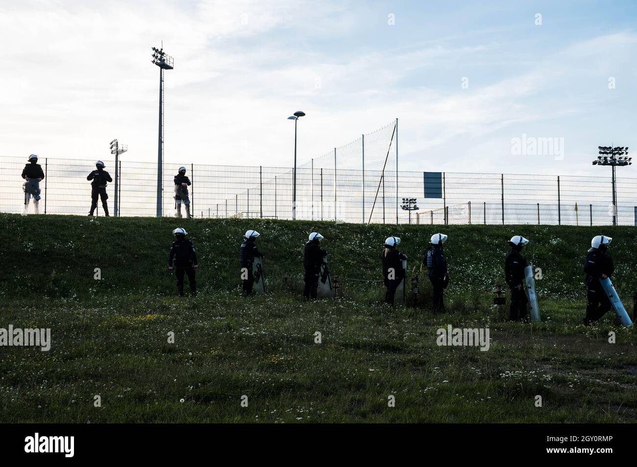 Silhouettes of policemen standing next to the football field (inscription in Polish Police) Stock Photo