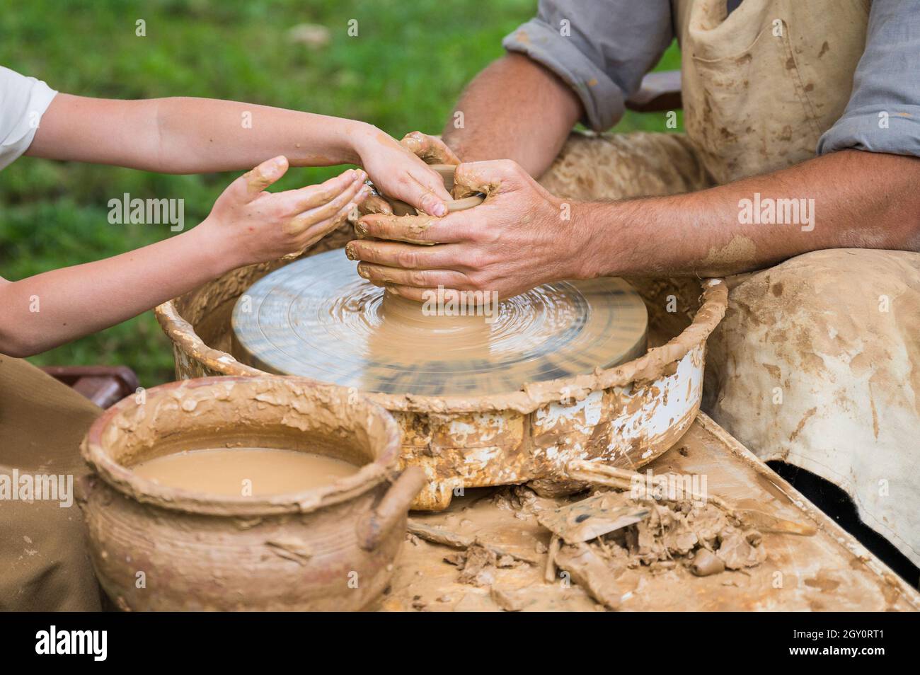 Hands of a child (student) and a man (teacher) during a pot making workshop Stock Photo
