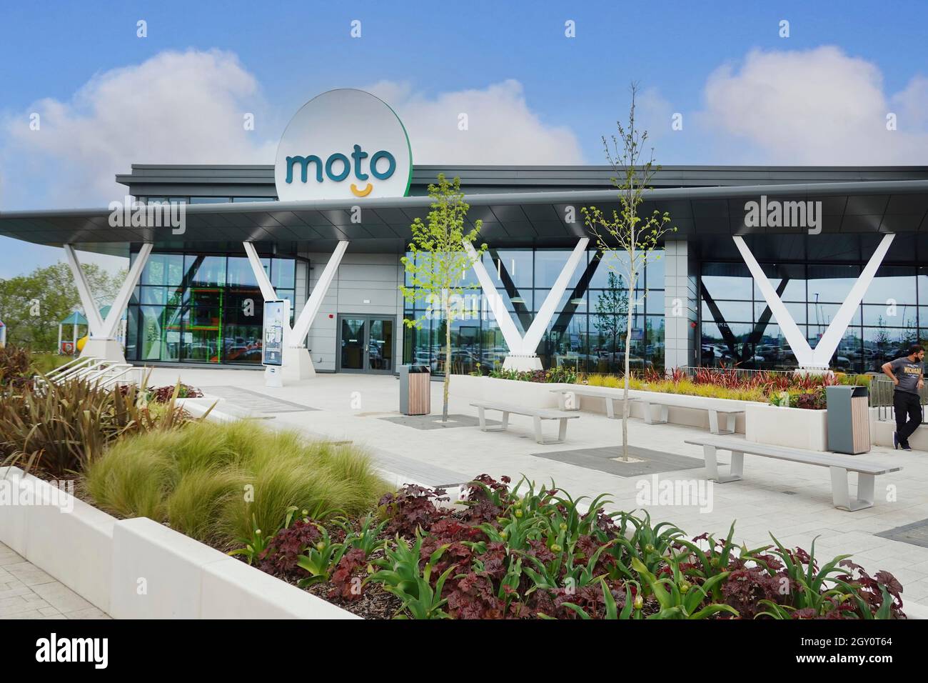 Outdoor seating in landscaping & flower planting at modern design of new Moto service station off M6 motorway Rugby junction Warwickshire England UK Stock Photo