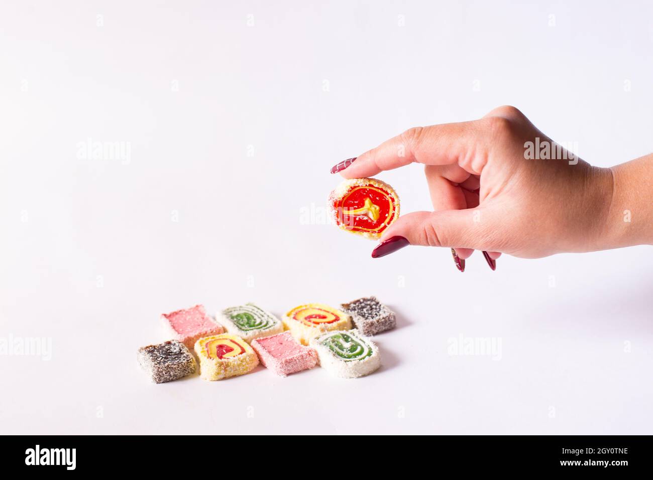 Turkish delight holding female hand bright orange color, on a white backgroud. Stock Photo