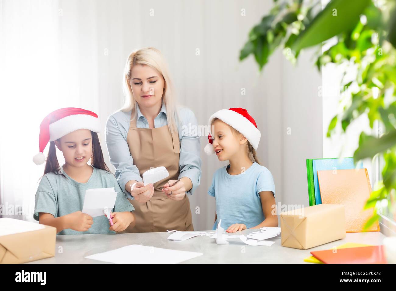 Young woman helping little daughters to make decoration for Xmas Stock ...