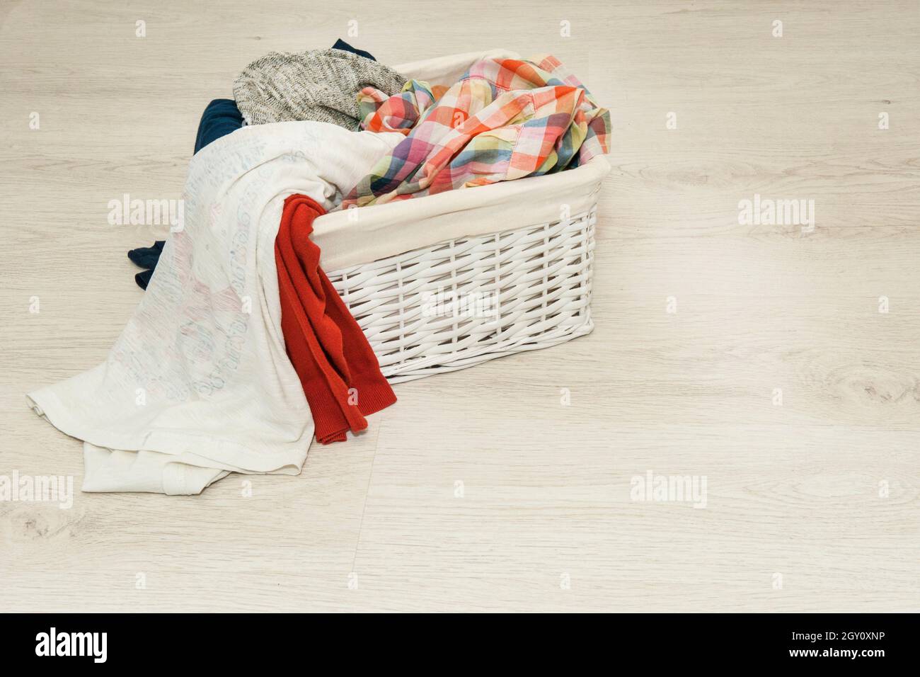 dirty laundry for washing in a wicker white basket Stock Photo