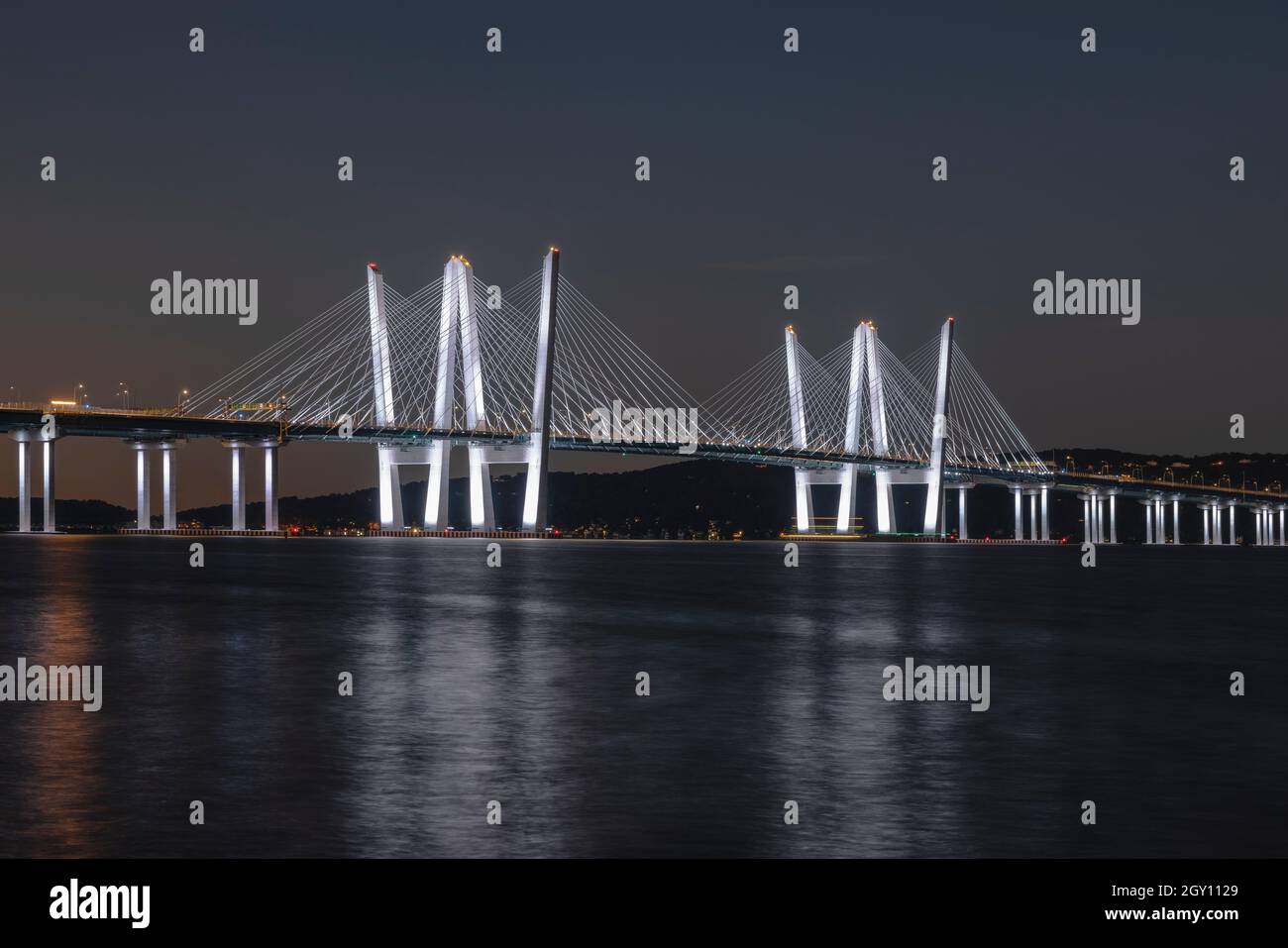 The Governor Mario M. Cuomo Bridge, illuminated with white lights, spans the Hudson River during morning twilight. Stock Photo