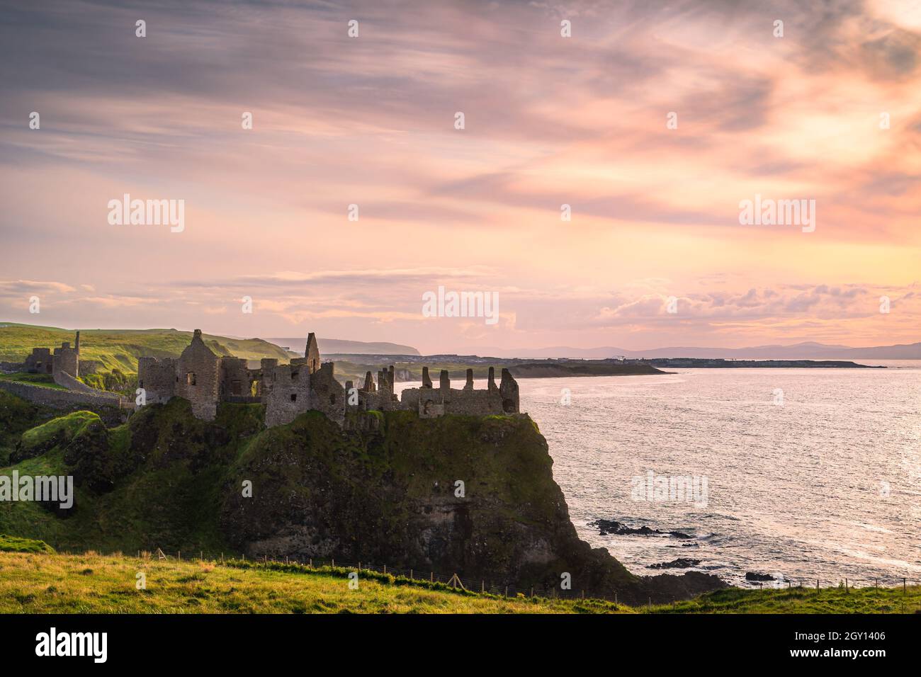 Dramatic sky over ruins of Dunluce Castle perched on the edge of cliff, Bushmills Northern Ireland Filming location of popular TV show Game of Thrones Stock Photo