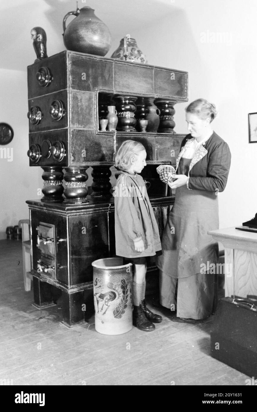 Eine Töpfermeisterin aus dem Kannenbäckerland zeigt einem kleinen Mädchen einen fertig gebrannten Tonkrug, Deutschland 1930er Jahre. A master potter is showing a finished stoneware jug to a little girl, Germany 1930s. Stock Photo