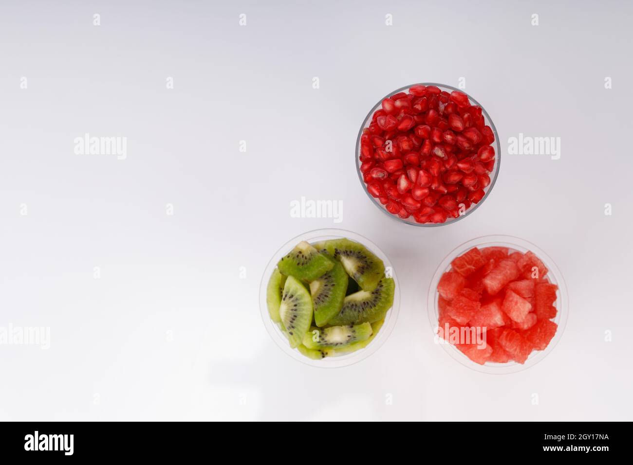 Watermelon , pomegranate and Kiwi Slices arranged  in two transparent glasses with white background, isolated Stock Photo