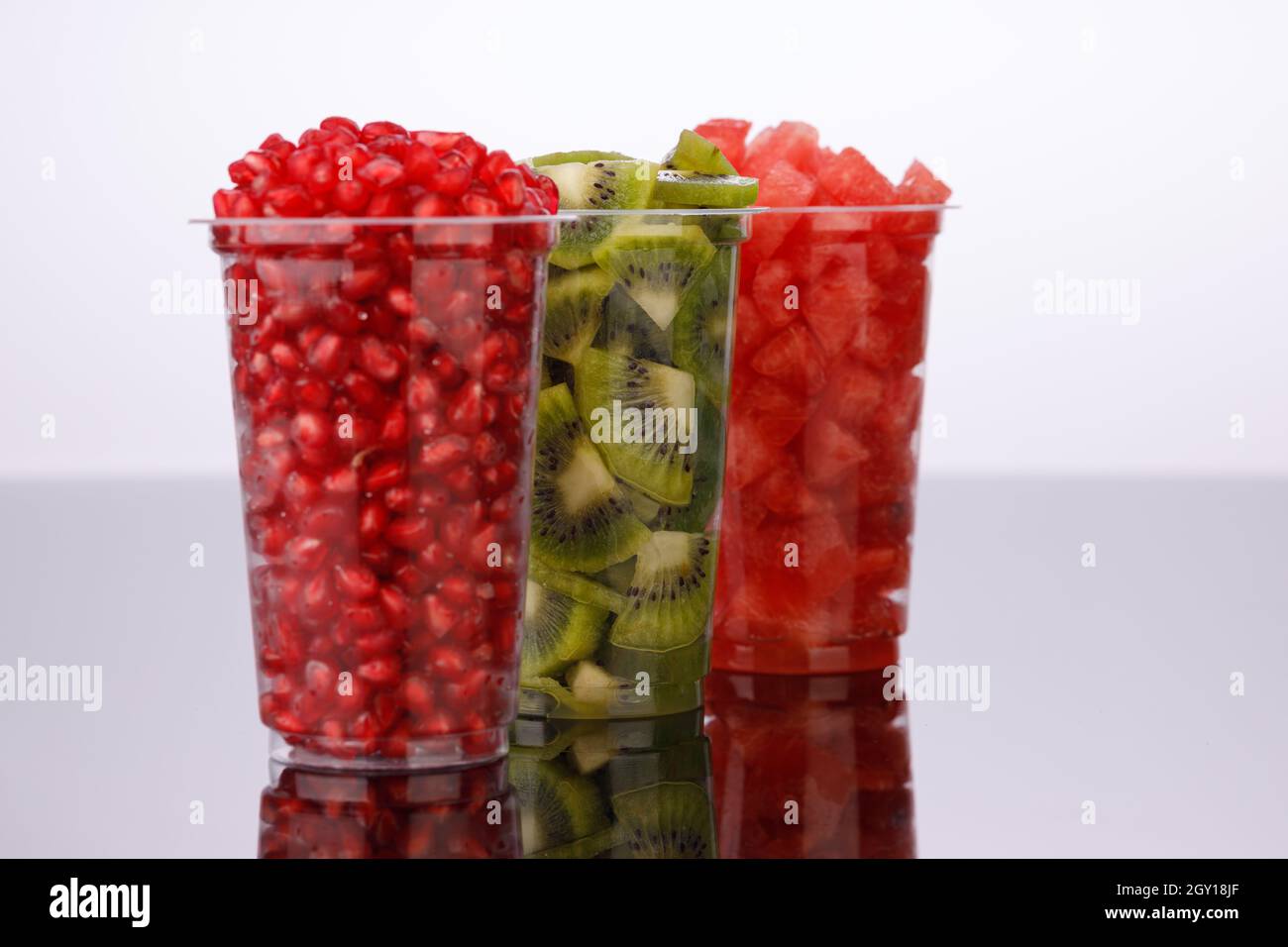 Watermelon , pomegranate and Kiwi  Slices arranged  in two transparent glasses with white background, isolated Stock Photo