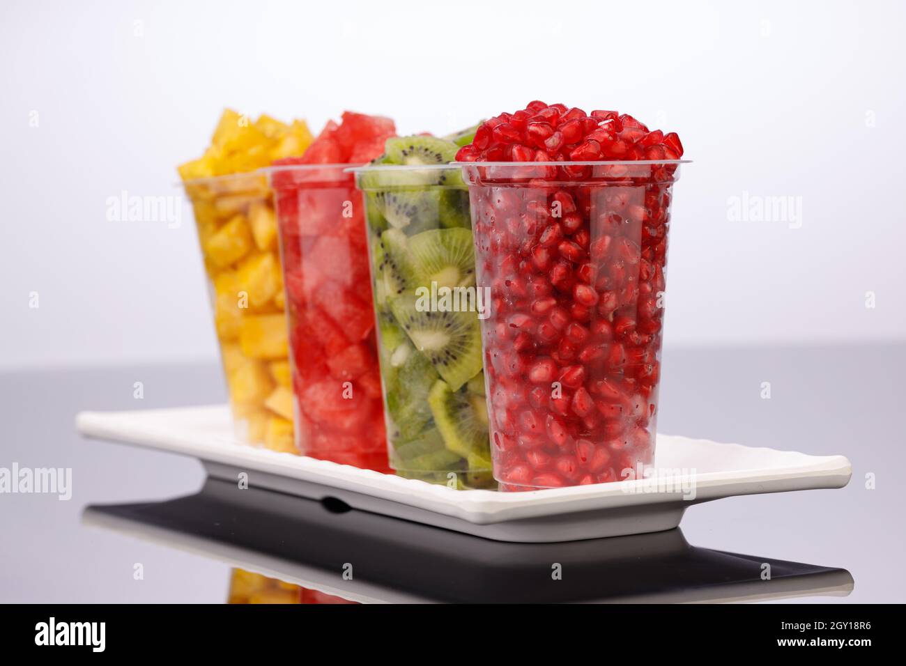Watermelon , pineapple  , pomegranate and Kiwi  Slices arranged  in  transparent glasses with white background, isolated Stock Photo