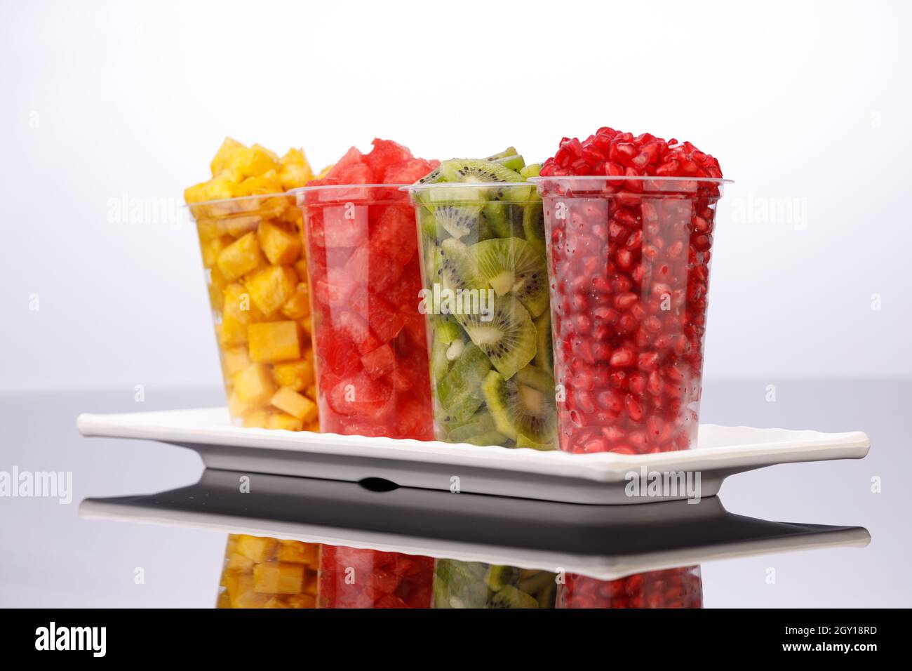 Watermelon , pineapple  , pomegranate and Kiwi  Slices arranged  in  transparent glasses with white background, isolated Stock Photo