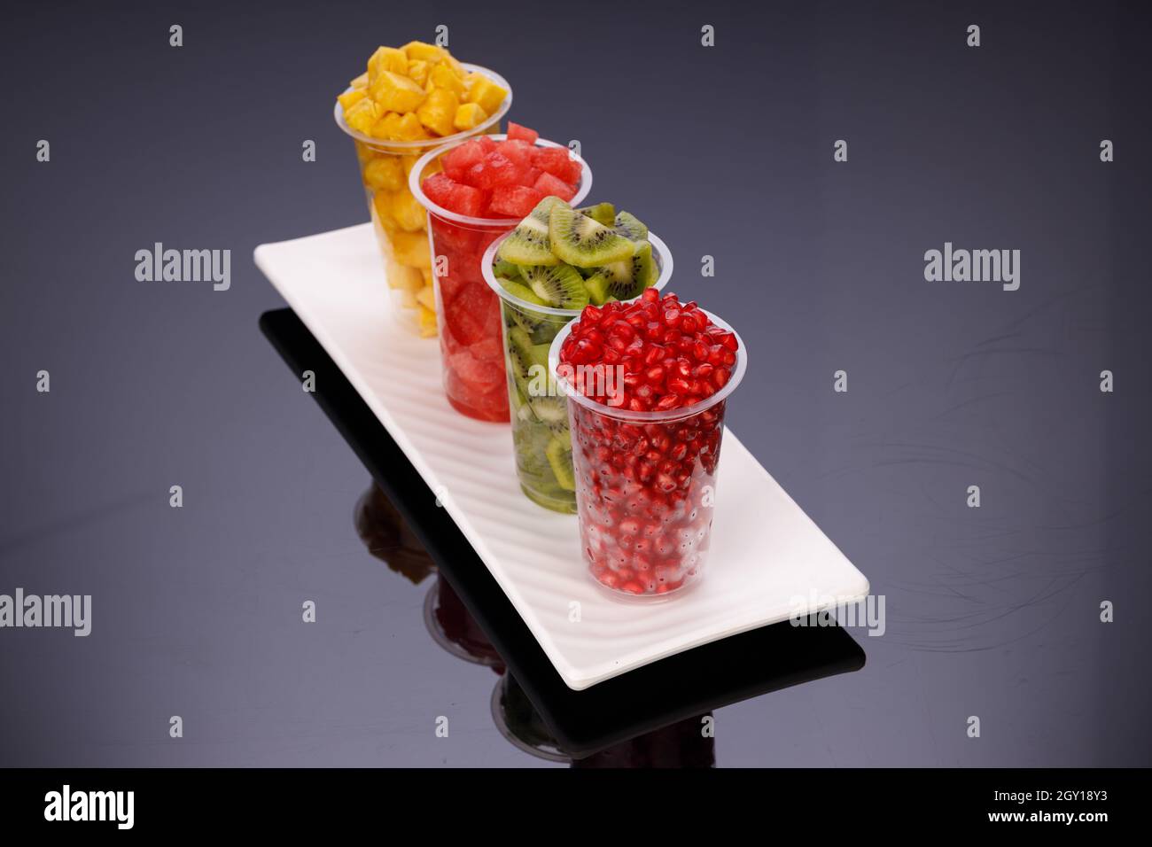 Watermelon , pineapple  , pomegranate and Kiwi  Slices arranged  in  transparent glasses with white background, isolated Stock Photo