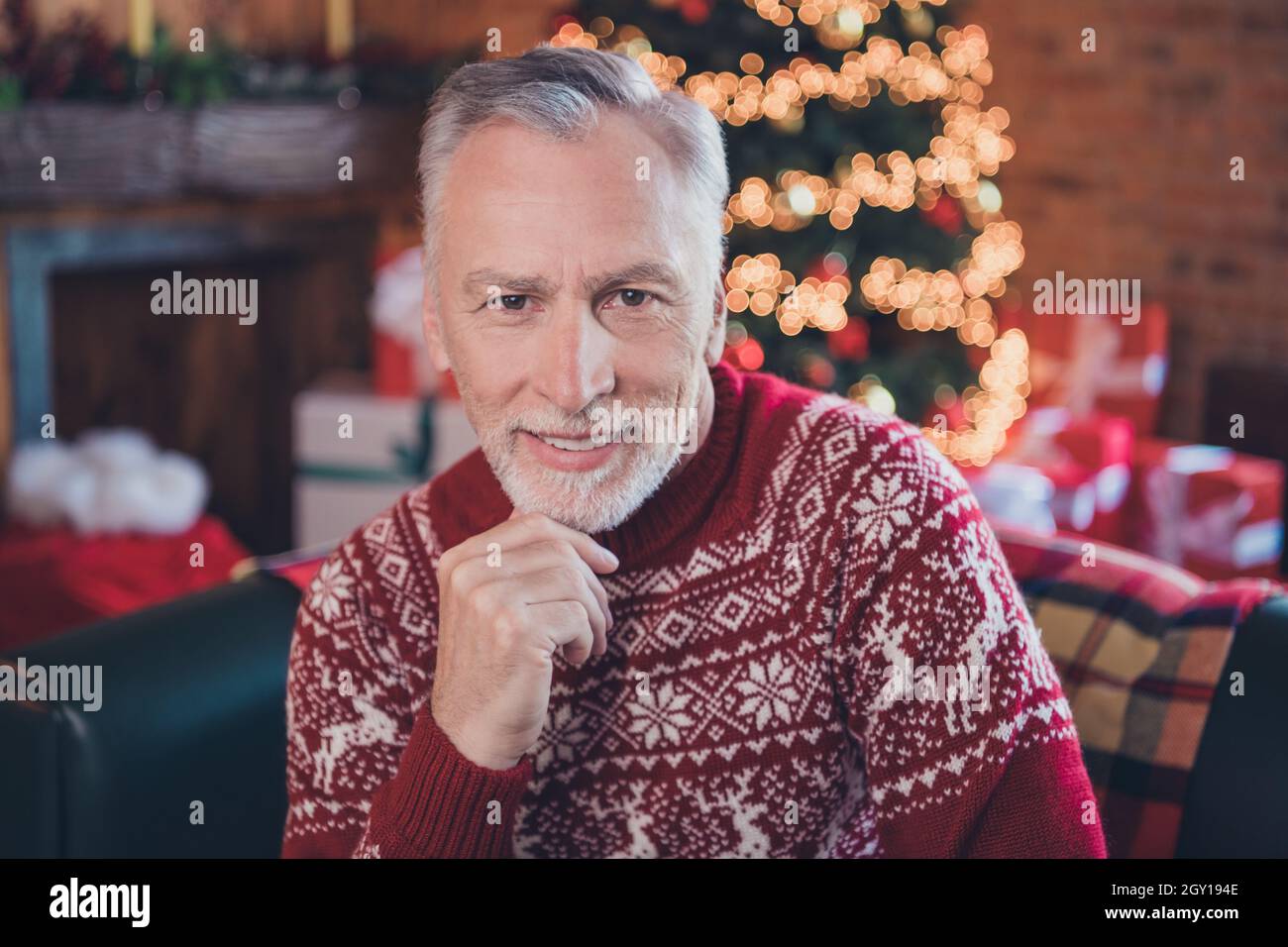 Photo portrait senior man smiling wearing sweater sitting on couch thoughtful Stock Photo