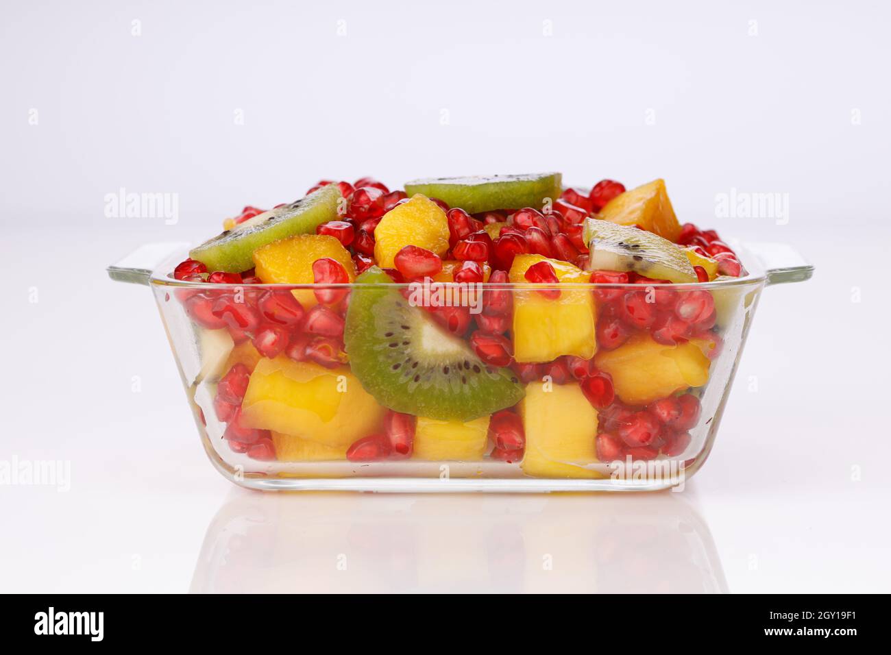 Mixed cut fruits arranged in a transparent glass bowl  with white background, isolated. Stock Photo