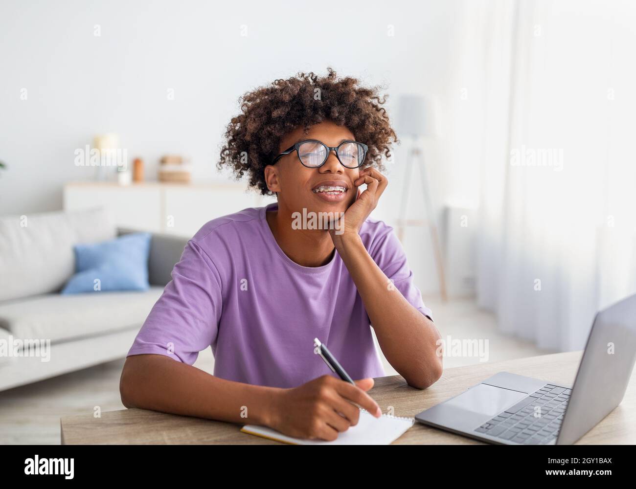 Home schooling, online education. Black teen sitting at desk with ...