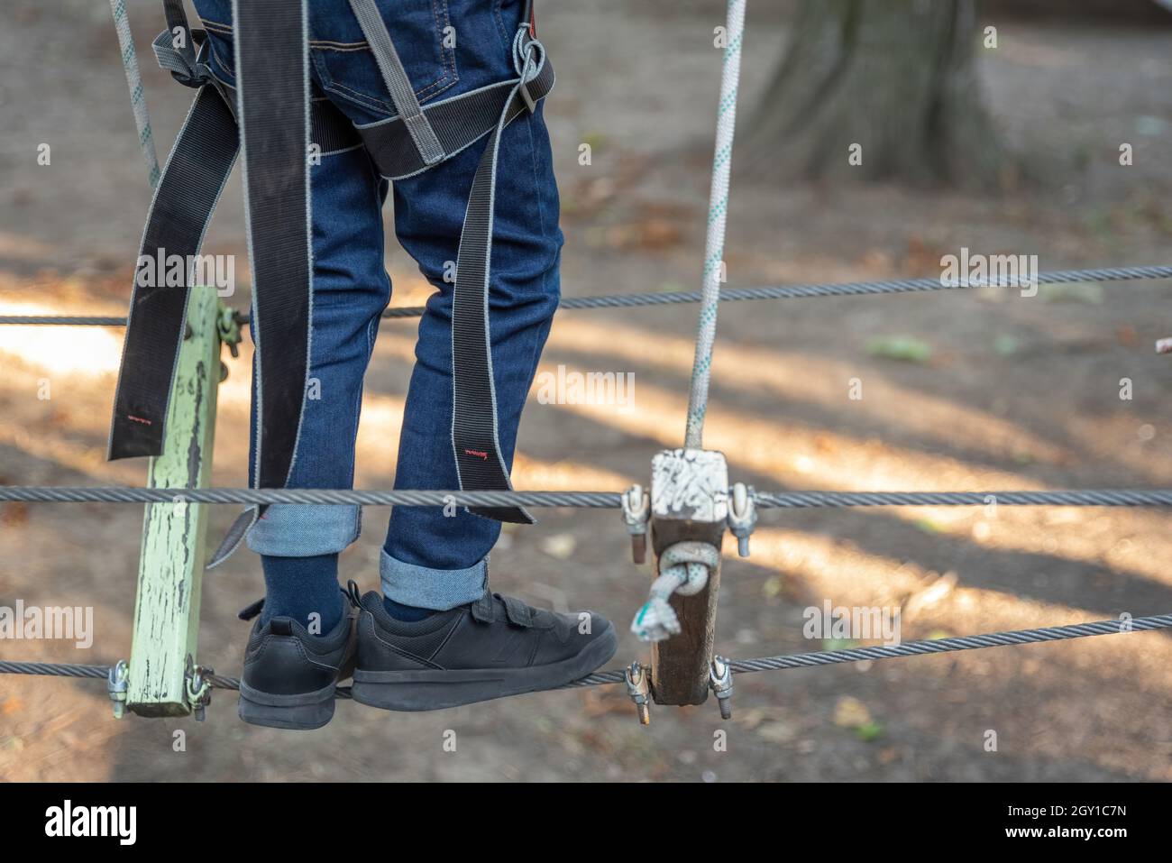 Close up of child's legs climbing on high rope park. Adventure climbing