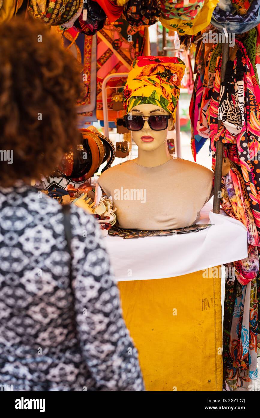 Woman looking at African head scarf on mannequin at Belo Horizonte Hippie Fair in Brazil. Stock Photo