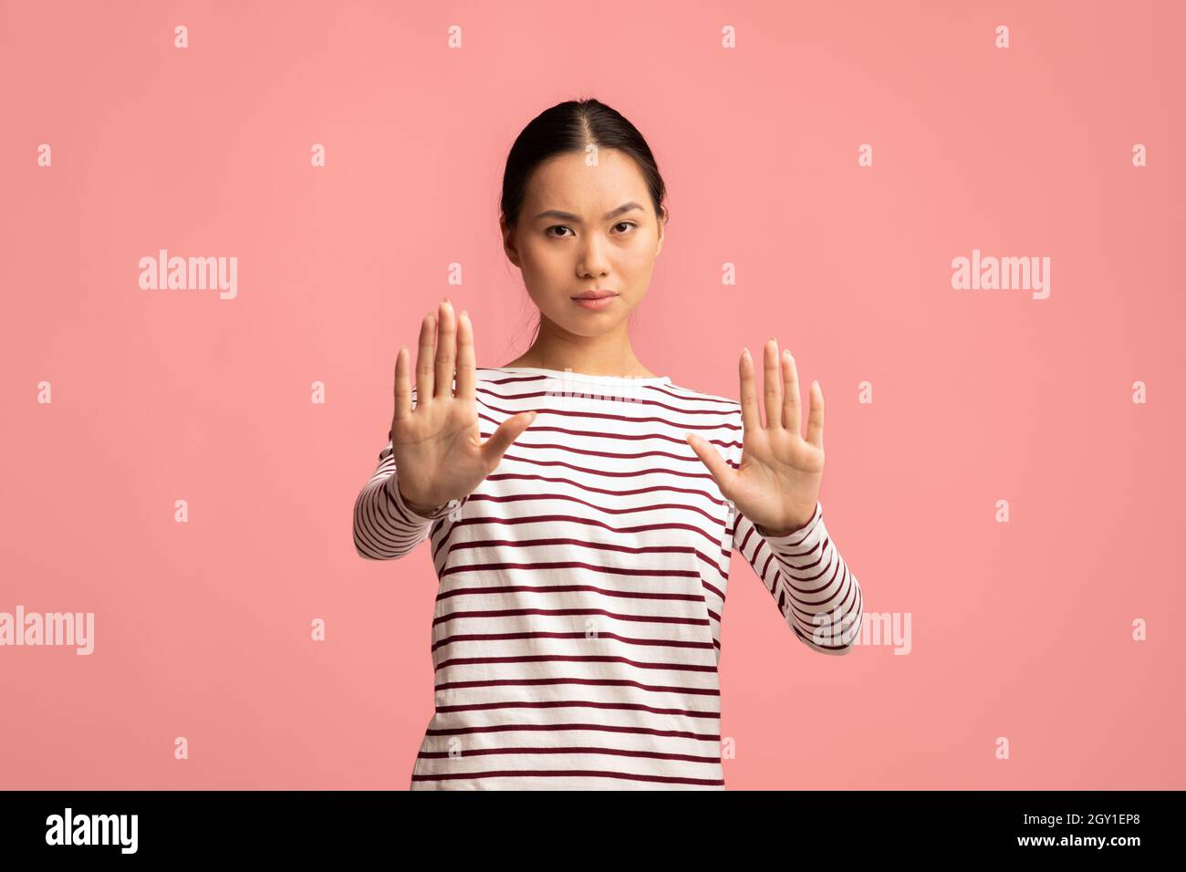Portrait Of Serious Young Asian Female Showing Stop Gesture At Camera Stock Photo
