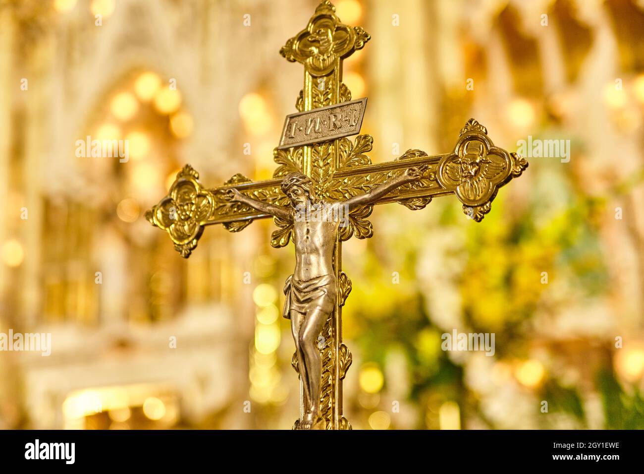 Close-up of an ornately decorated crucifix with the back wall of the sanctuary in the background Stock Photo