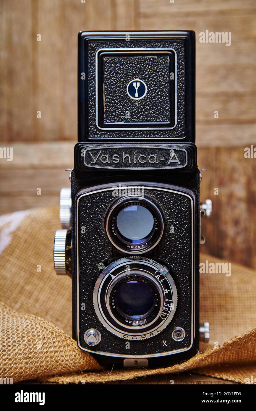 Very old style camera on top of burlap material in front of a wood wall