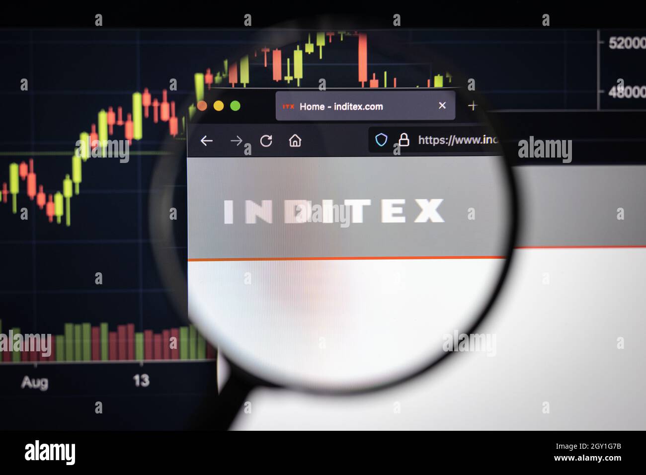 Inditex company logo on a website with blurry stock market developments in the background, seen on a computer screen through a magnifying glass Stock Photo