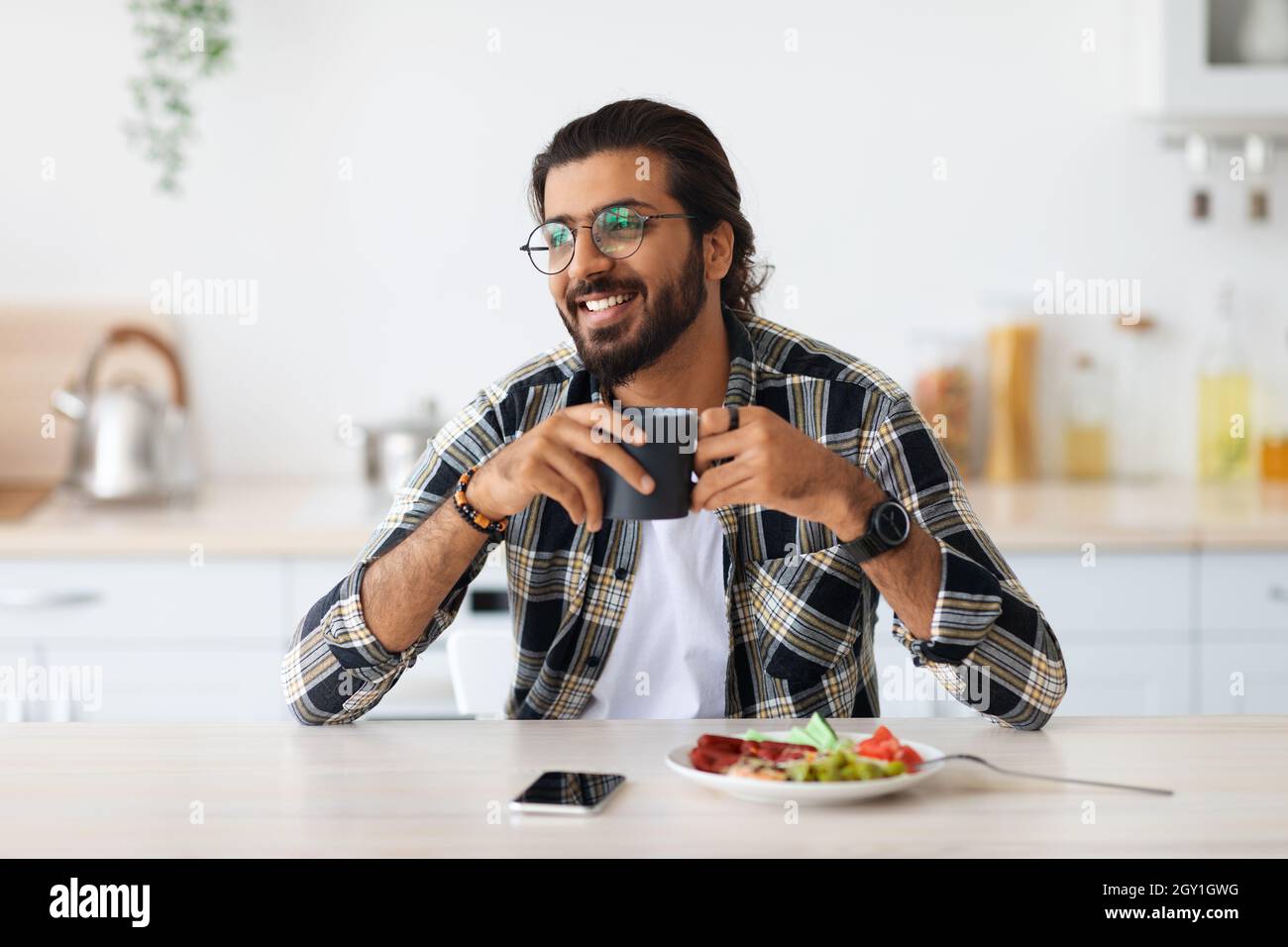 Smiling arab guy having breakfast, looking at copy space Stock Photo