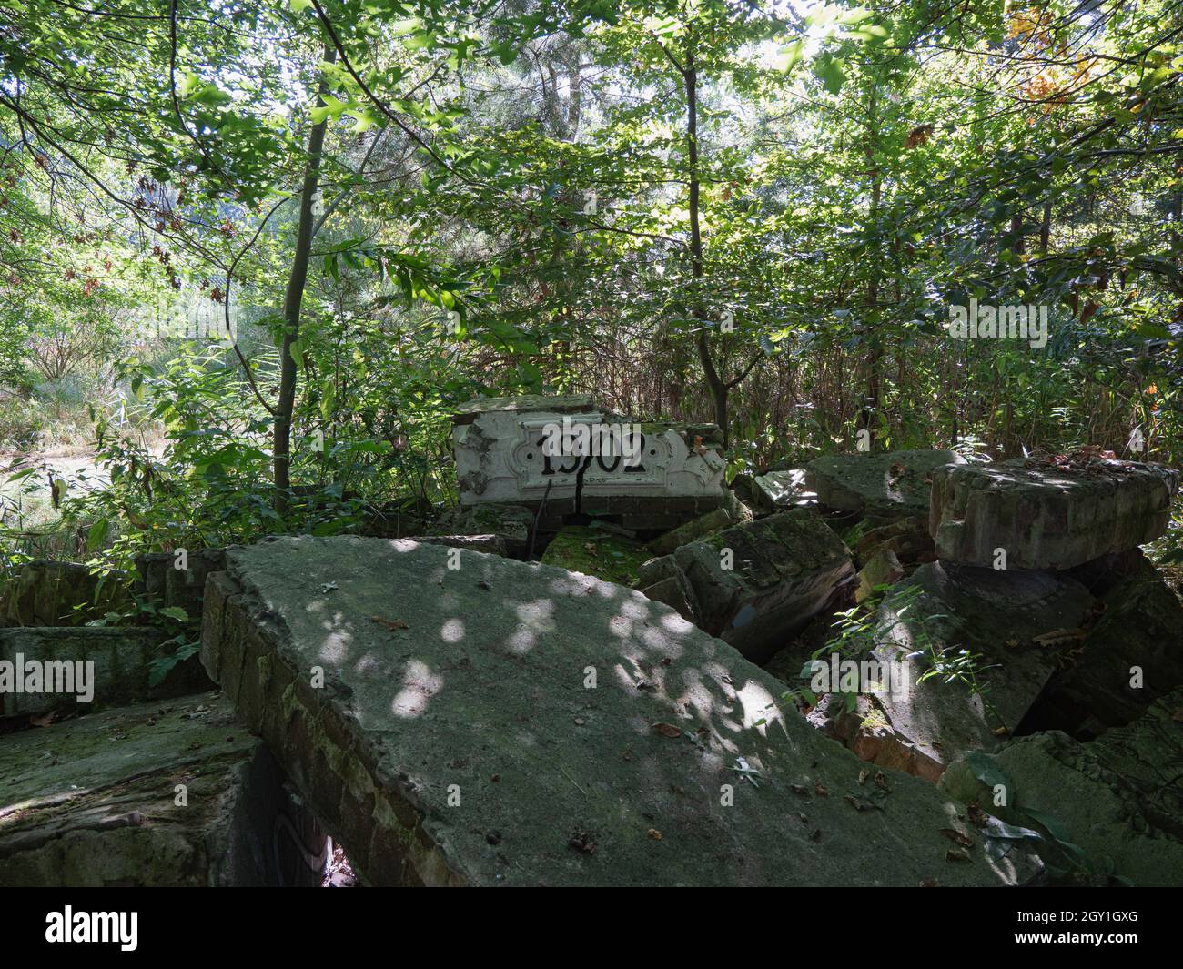Remains of an abandoned collapsed house in the middle of a forest built in 1902 with a broken stone indicating the year Stock Photo