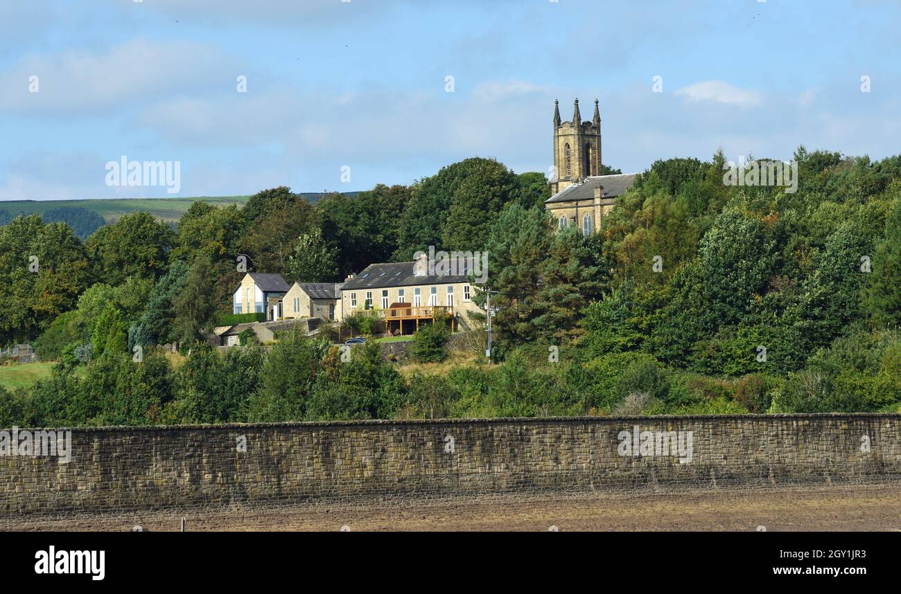 Village of Tintwistle on a Derbyshire hillside church houses and trees