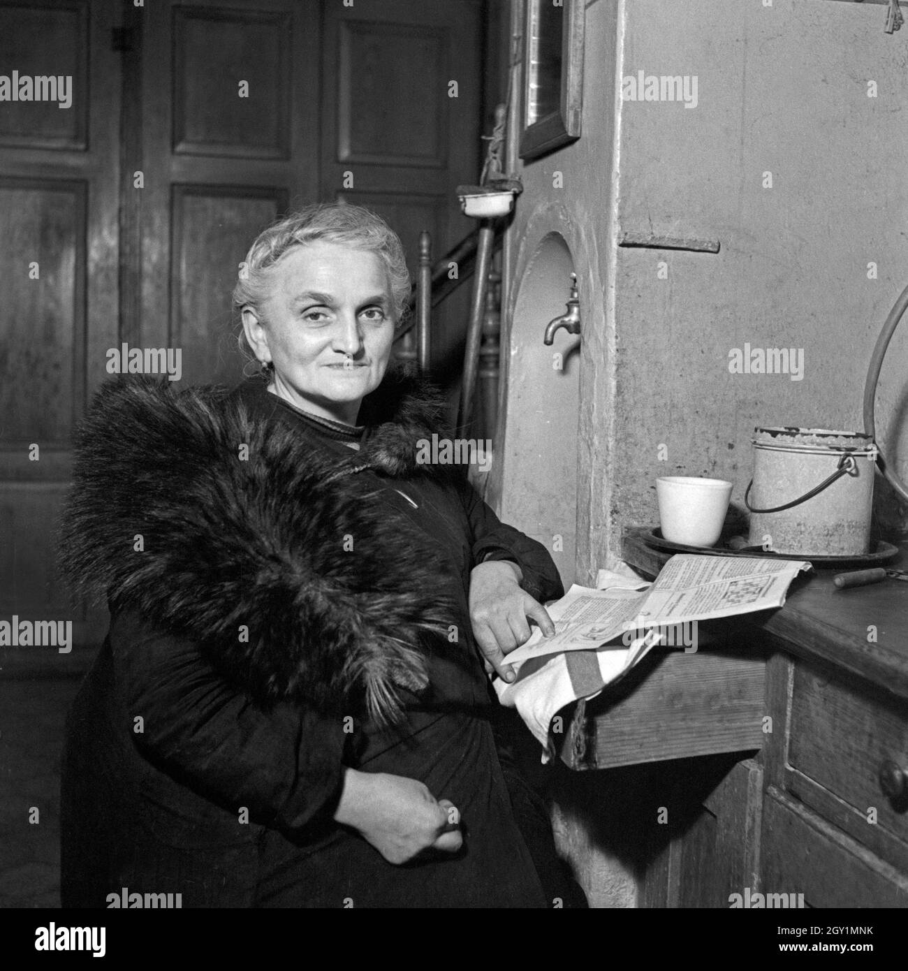 Eine alte Frau hält sich mit einem Fell warm, Deutschland 1930er Jahre. A senior woman keeps herself war with a fur, Germany 1930s. Stock Photo