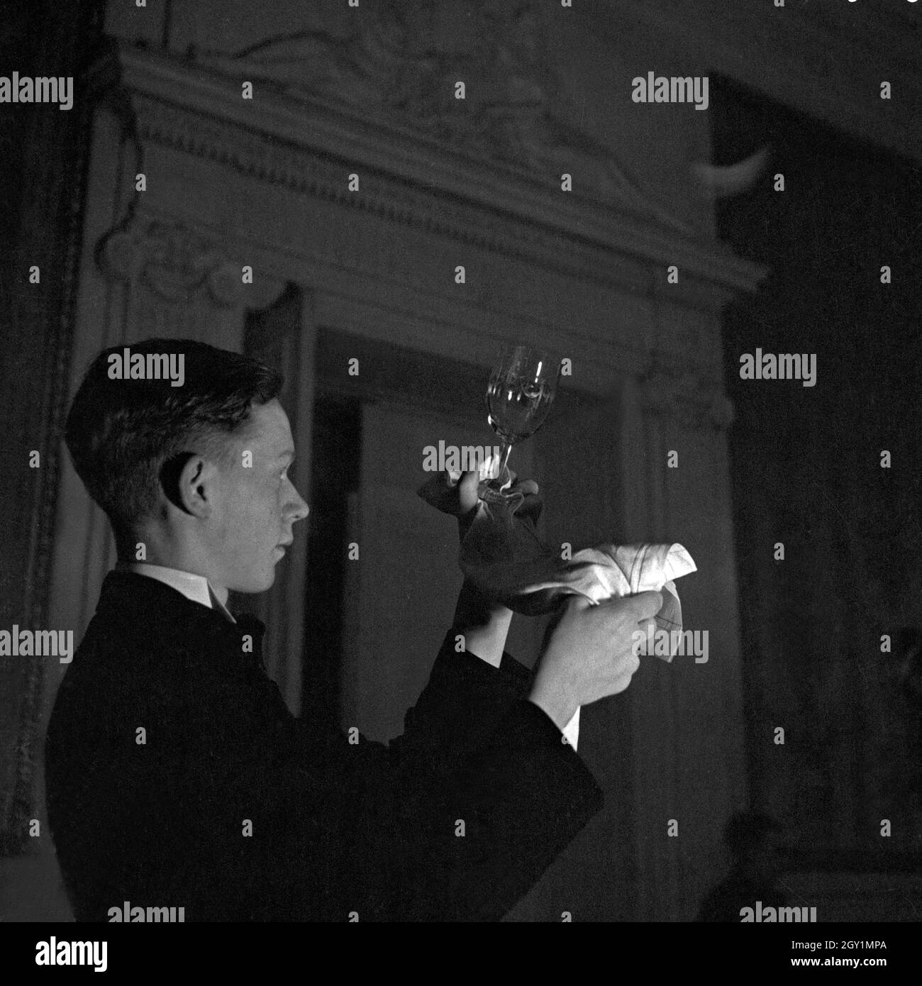 Ein Lehrjunge in einem Restaurant bringt die Gläser auf Hochglanz im Reichsberufswettkampf 1937, Deutschland 1930er Jahre. A trainee of a restaurant polishing glasses at the Reichsberufswettkampf contest 1937, Germany 1930s. Stock Photo